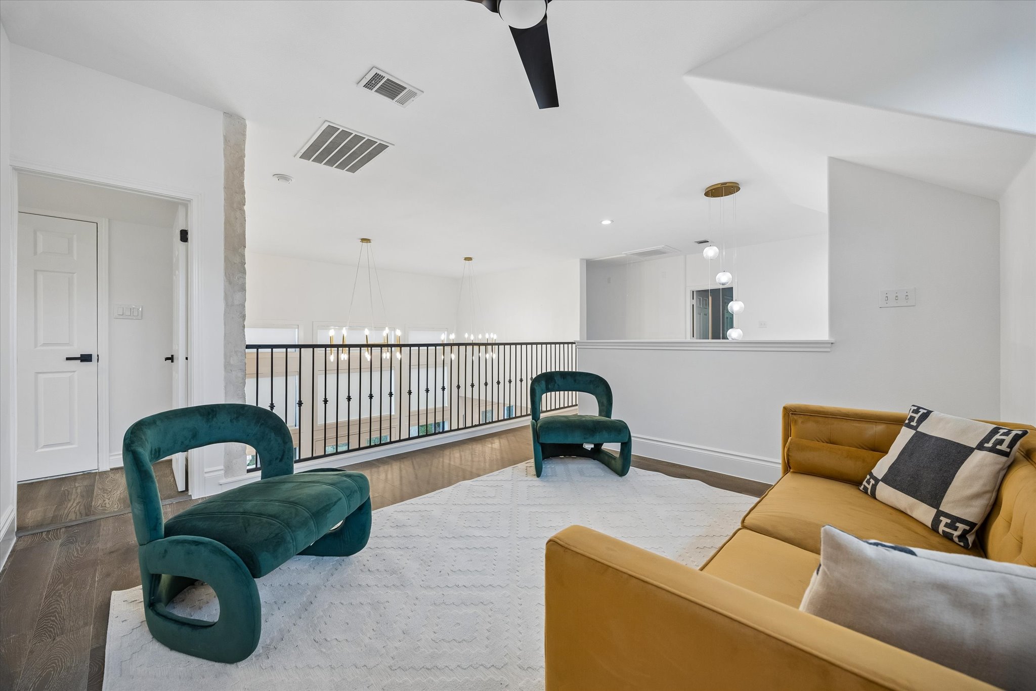 3719 Bee Creek Road Spicewood, TX 78669 - Photo 20 of 40 A well-lit upper-level landing features dark hardwood flooring and a stylish black metal railing overlooking the floor below.