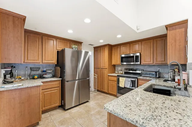 a kitchen with stainless steel appliances granite countertop a refrigerator stove microwave sink and cabinets