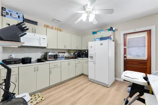 a kitchen with a refrigerator a stove a sink dishwasher and white cabinets with wooden floor