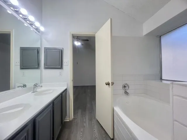 a bathroom with a tub a sink and mirror