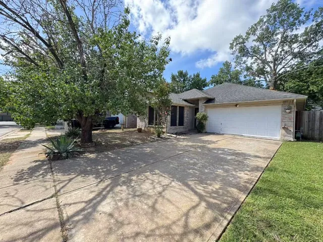 a backyard of a house with table and chairs under an umbrella