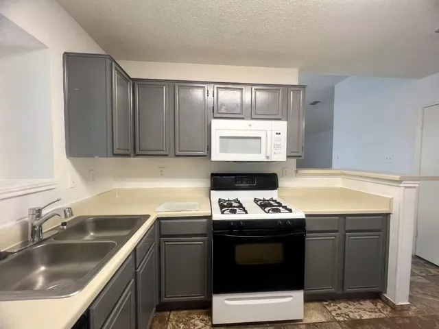 a kitchen with stainless steel appliances a stove sink and microwave