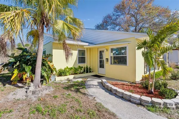 a front view of a house with a yard and potted plants