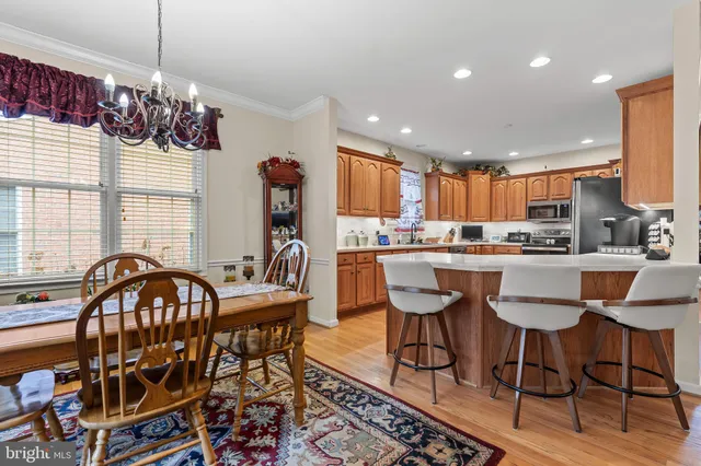 a kitchen with stainless steel appliances granite countertop a dining table chairs stove a sink and dishwasher a fireplace with wooden floor