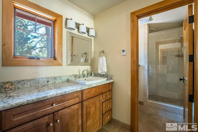 a bathroom with a granite countertop sink a mirror and a shower