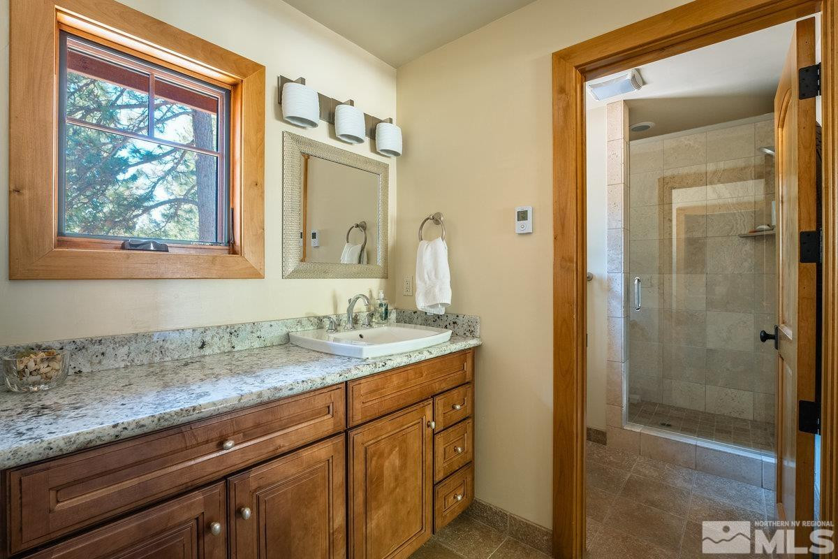 2147 The Back Road Glenbrook, NV 89413 - Photo 20 of 40 a bathroom with a granite countertop sink a mirror and a shower