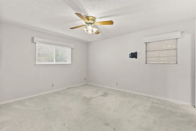 an empty room with windows and fan