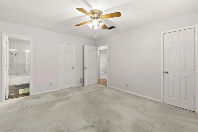 an empty room with closet and a chandelier fan