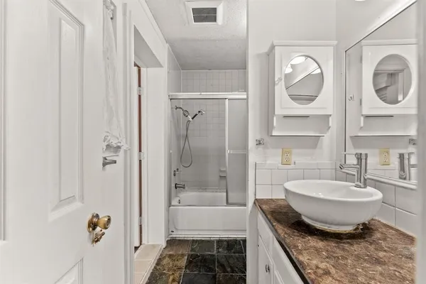 a bathroom with a granite countertop bathtub shower sink and mirror