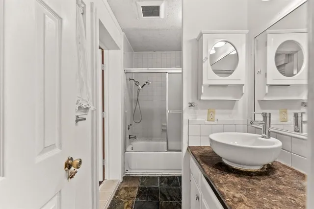 a bathroom with a granite countertop bathtub shower sink and mirror
