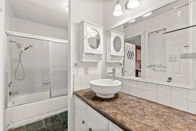 a bathroom with a granite countertop sink toilet a mirror a bathtub and shower