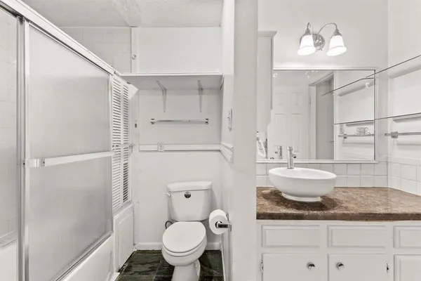 a bathroom with a granite countertop sink a toilet and shower