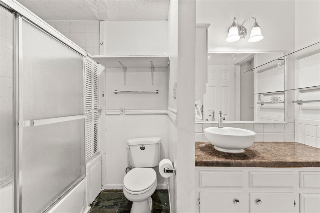 3013 Arapaho Road Commerce, TX 75428 - Photo 18 of 34 a bathroom with a granite countertop sink a toilet and shower