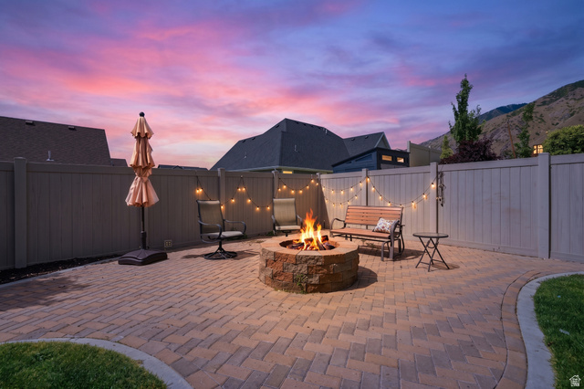 1997 East 600 South Springville, UT 84663 - Photo 50 of 54 Paver patio with a stone fire pit, string lighting, and privacy fencing