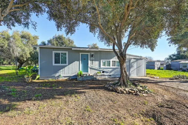 a view of a house with a big yard and large trees