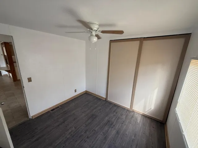 an empty room with wooden floor and a ceiling fan