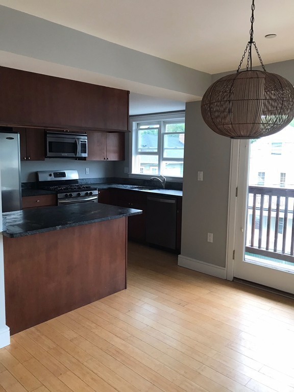 2 Boylston Street, Unit 3 Boston, MA 02130 - Photo 5 of 9 a kitchen with granite countertop a stove a sink and a microwave