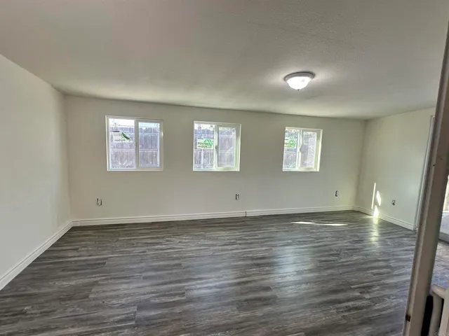 a view of an empty room with wooden floor and windows