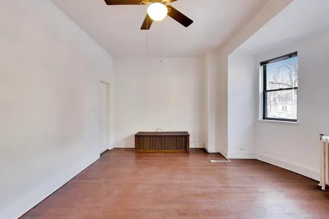 a view of an empty room with window and wooden floor