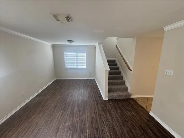 a view of an empty room with wooden floor and staircase