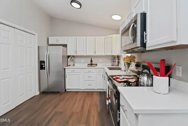 a view of a kitchen with a sink stove cabinets and empty room
