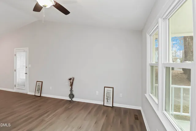 a view of empty room with wooden floor and fan