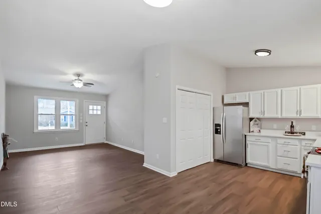 a kitchen with a refrigerator a sink dishwasher a stove and white cabinets with wooden floor