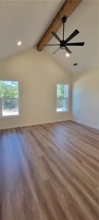 an empty room with wooden floor ceiling fan and windows