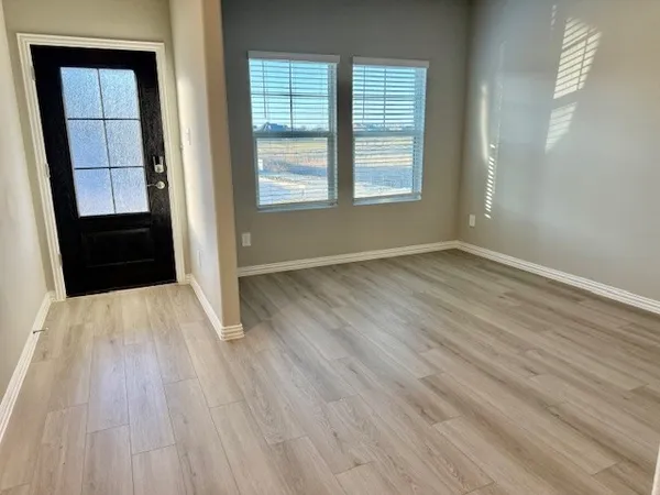 an empty room with wooden floor and windows