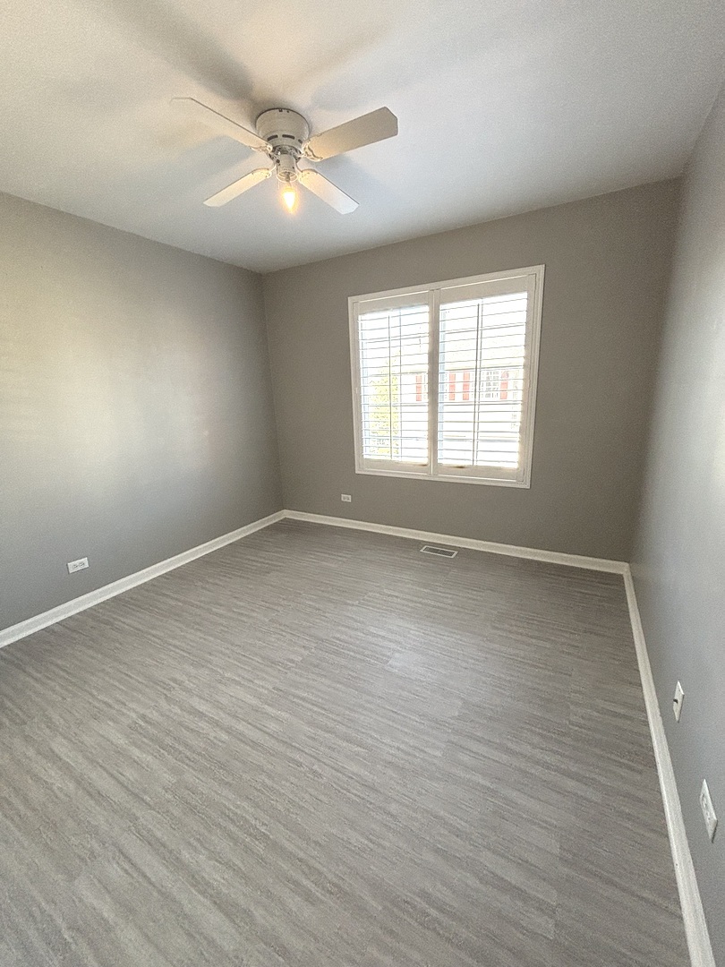 268 Windsor Court, Unit D South Elgin, IL 60177 - Photo 19 of 21 an empty room with wooden floor and windows