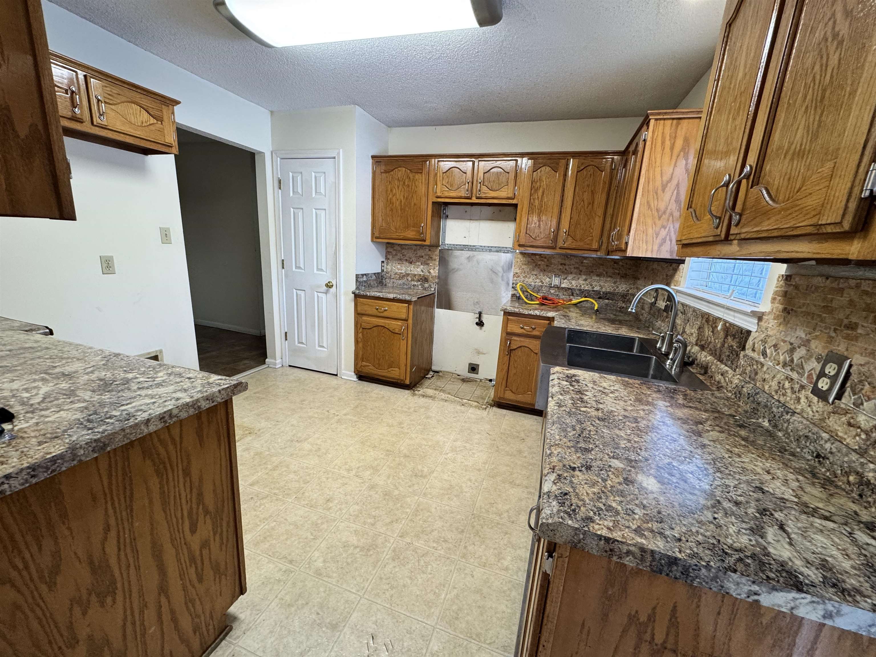 7916 Macon Road Memphis, TN 38018 - Photo 15 of 24 Kitchen featuring a textured ceiling, wood finish cabinets, tasteful backsplash, and dark countertops