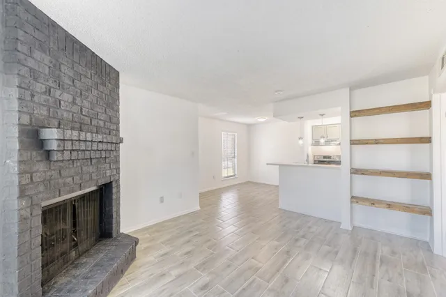 a view of empty room with wooden floor and fireplace