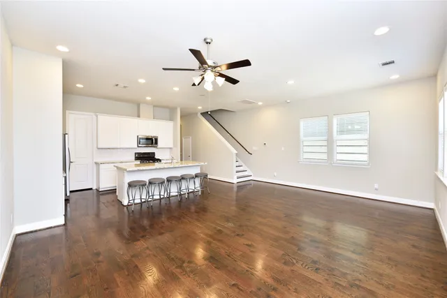 an open kitchen with dining table wooden floor and a ceiling fan