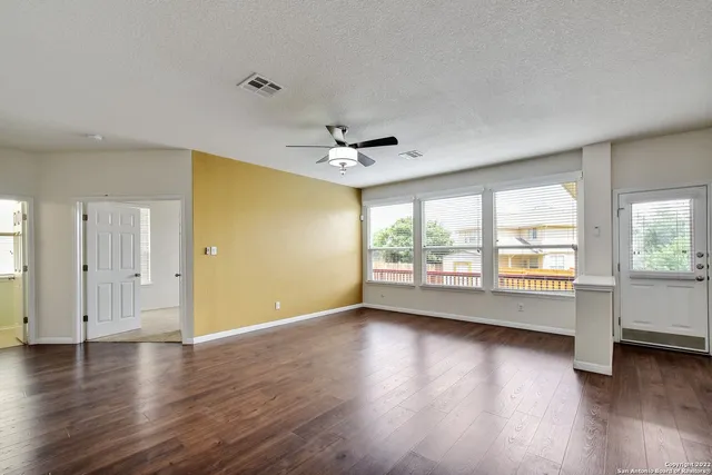 an empty room with wooden floor and windows