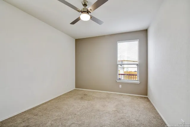 an empty room with a window and a fan