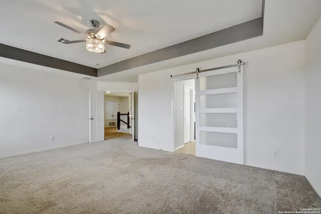 a view of an empty room with a chandelier fan