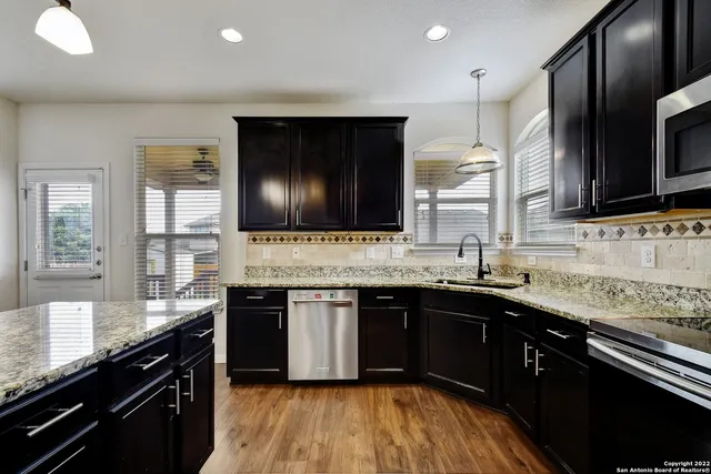 a large kitchen with granite countertop a sink and a stove top oven with wooden floor