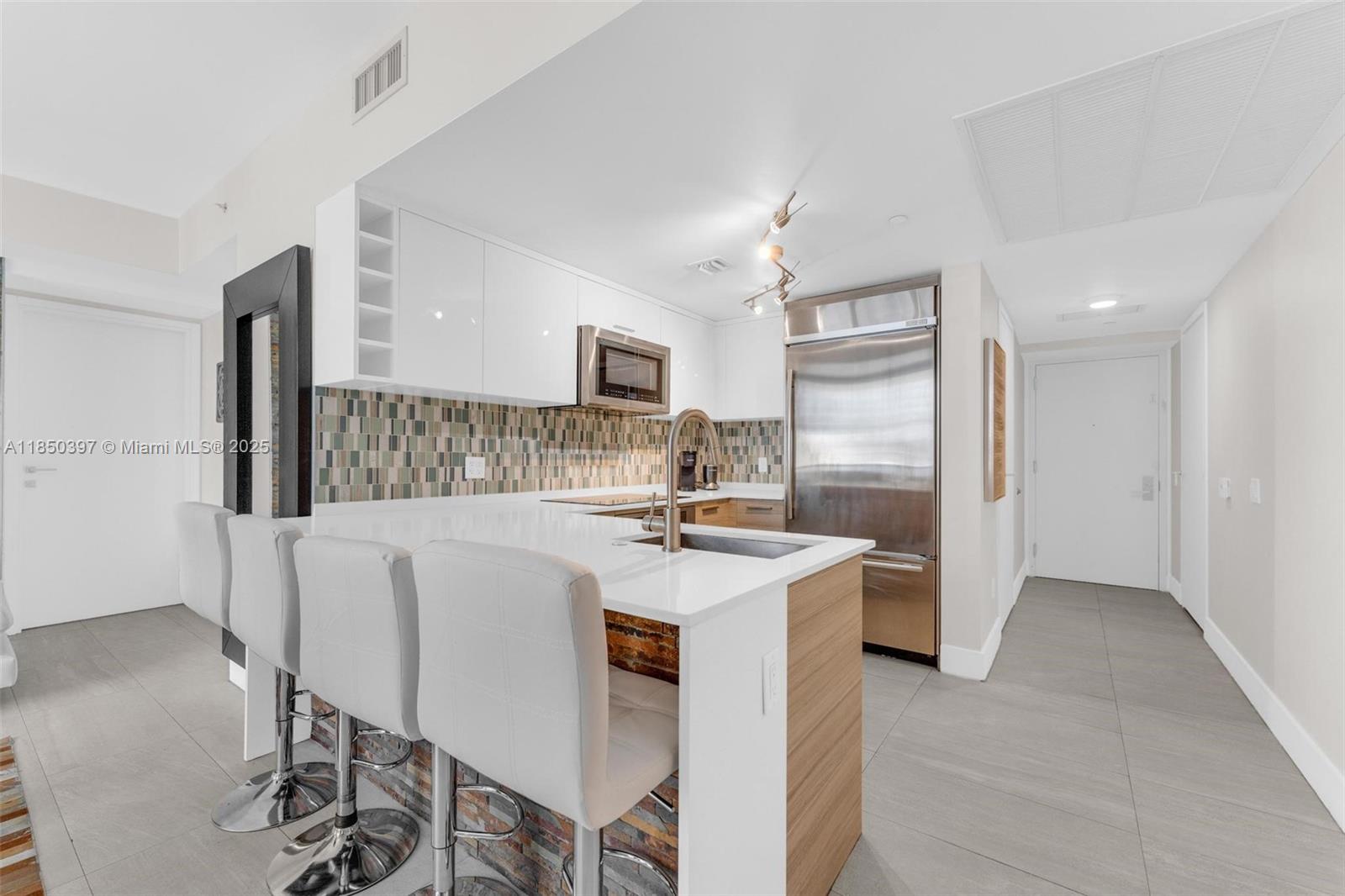 1300 Brickell Bay Drive, Unit 2511 Miami, FL 33131 - Photo 6 of 30 a kitchen with stainless steel appliances a table and chairs in it