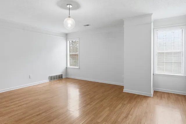 a view of an empty room with wooden floor and a window