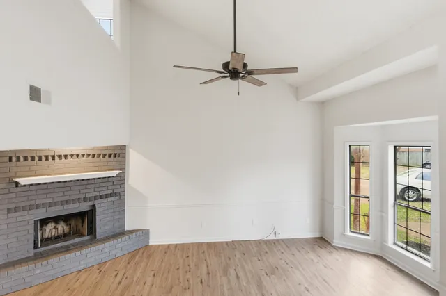 an empty room with windows and fireplace