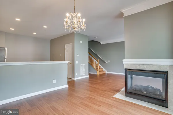a view of an empty room with wooden floor fireplace and a window