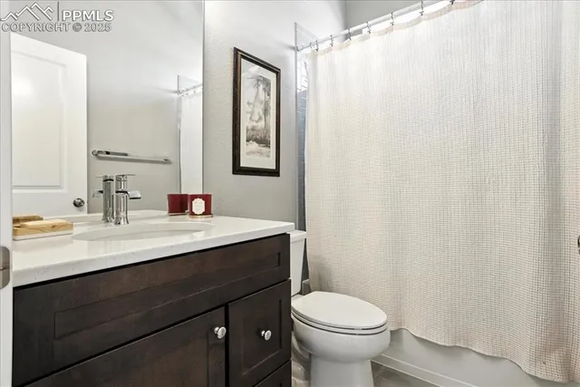 a bathroom with a sink a toilet a mirror and shower curtain
