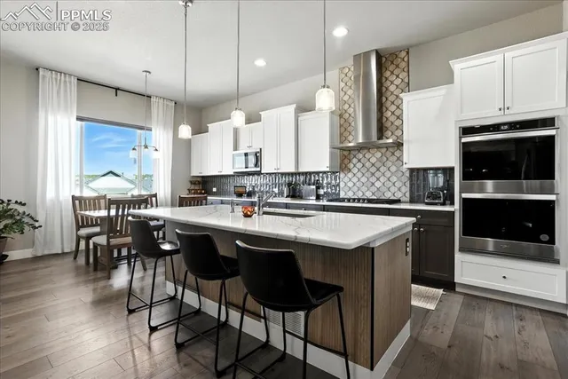 a kitchen with stainless steel appliances granite countertop a table chairs sink and cabinets