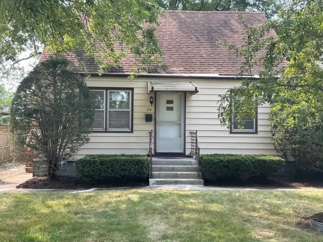 a view of a house with a yard plants and large tree