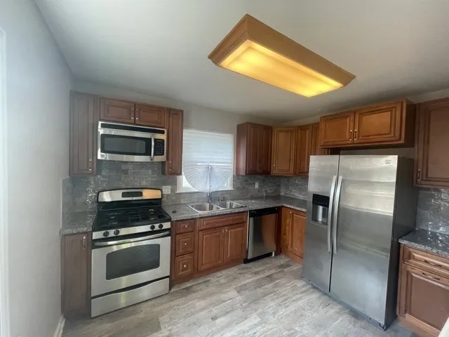 a kitchen with granite countertop a refrigerator stove and microwave