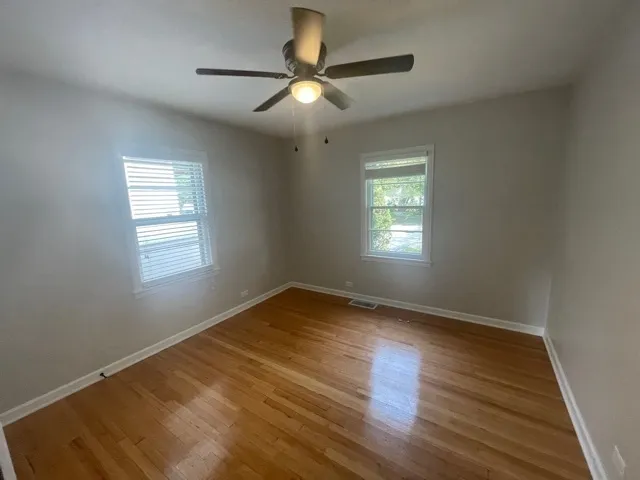 a view of empty room with wooden floor and fan
