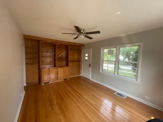 a view of an empty room with a window and wooden floor