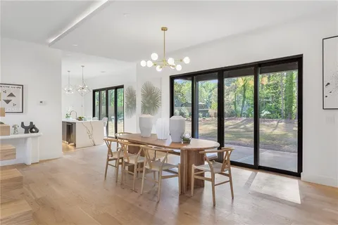 a view of a dining room and livingroom with furniture wooden floor a chandelier