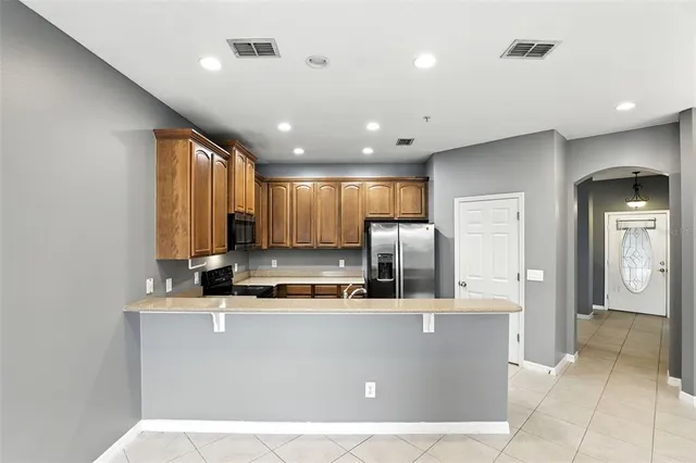 a kitchen with kitchen island stainless steel appliances a sink a counter top space cabinets and a window