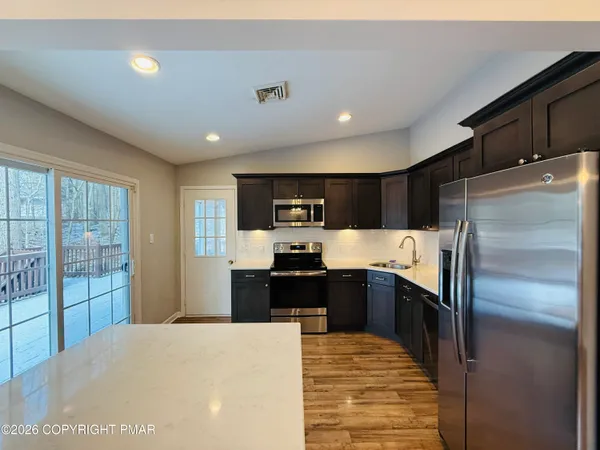 a large kitchen with stainless steel appliances kitchen island granite countertop a refrigerator and a sink